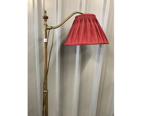 A contemporary brass standard lamp with red shade