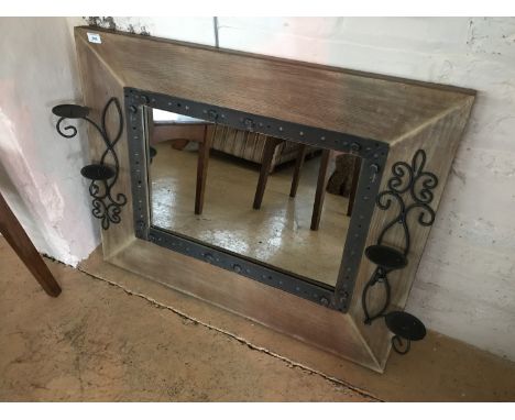 A contemporary wall mirror with wrought candle sconces