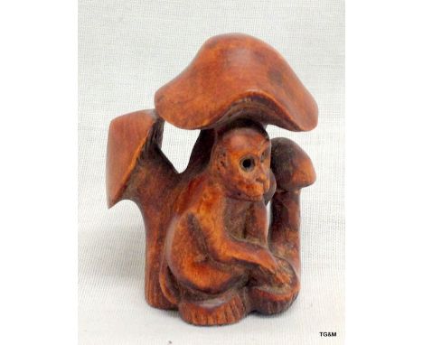 An oriental rosewood netsuke in the form of a monkey amongst mushrooms