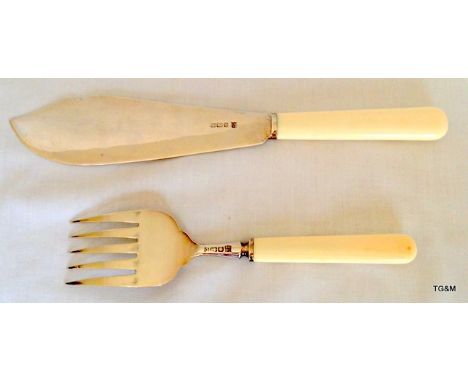 A silver fish slice and fork with ivory handles