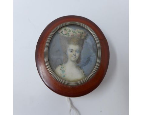 An 18th century miniature portrait of a lady, mounted in white metal on the lid of an amber tobacco box, H.7cm 