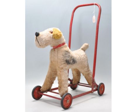 A vintage 20th Century&nbsp;Chiltern made push / ride along&nbsp;dog fixed to a tubular red painted metal trolley frame. Labe