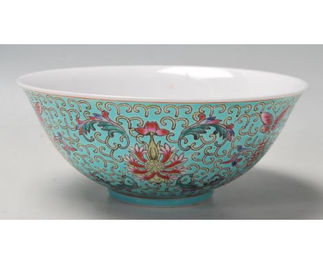 A vintage 20th Century Chinese bowl decorated with floral, butterfly and Shou emblem designs on a turquoise ground in the fam