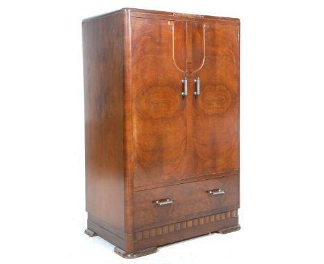 A 1930's Art Deco walnut bachelors wardrobe cabinet having twin panelled doors and a shelved interior atop a single drawer. R