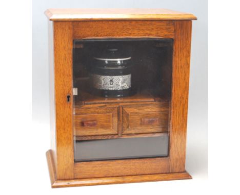 A late 19th century Victorian Art and Crafts oak smokers cabinet having a chamfered top over a bevelled glass hinged door wit