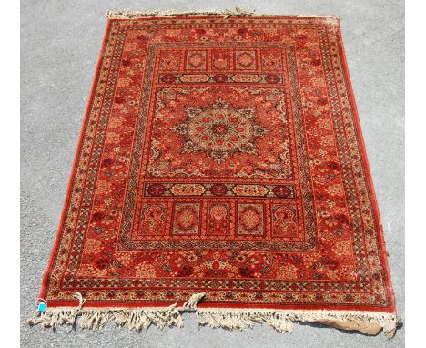 A vintage Persian Islamic rug carpet having a red background with a central star motif surround by geometric shapes with tass