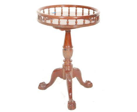 A Victorian 19th Century mahogany style wine table having a spindle gallery top above a turned column and carved tripod legs 