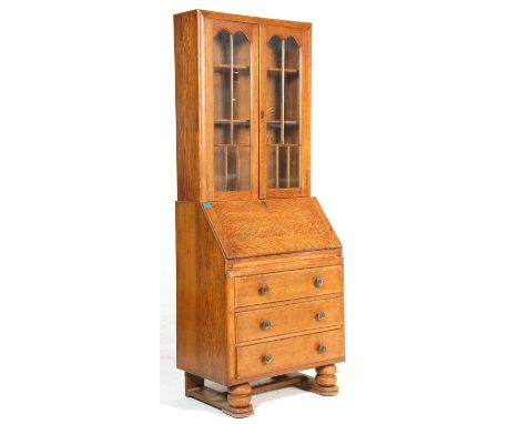 A 1930's Art Deco light oak bureau bookcase. The bookcase with a glazed double door enclosing shelves above a fall front desk