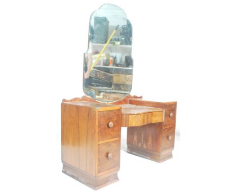 A 1930's Art Deco twin pedestal walnut dressing table. The dressing table with shaped bevelled articulated mirror above a dro
