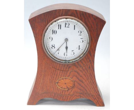 An early 20th Century French oak mantel / mantle clock having a round white enamelled face with arabic numerals to the chapte