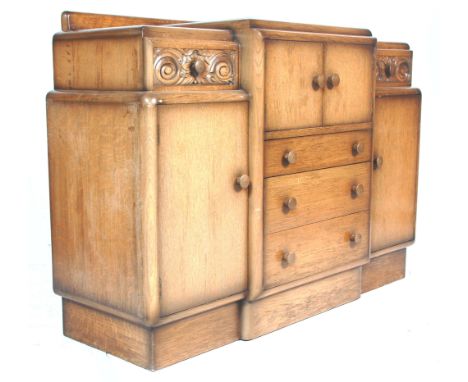 A vintage 1930's Art Deco oak breakfront sideboard having a stub stage gallery back over&nbsp; twin door cupboard and chest o