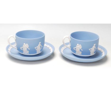 A pair of antique early 20th century Wedgwood dancing hours Jasperware tea cups and saucers with raised classical decoration 