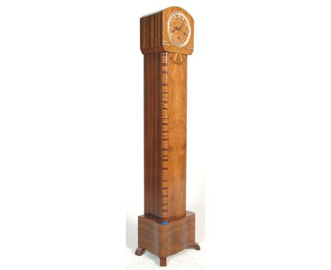 An Art Deco 1930's figured walnut grandmother clock. The Art Deco case having a silvered chapter ring to the face and inset b
