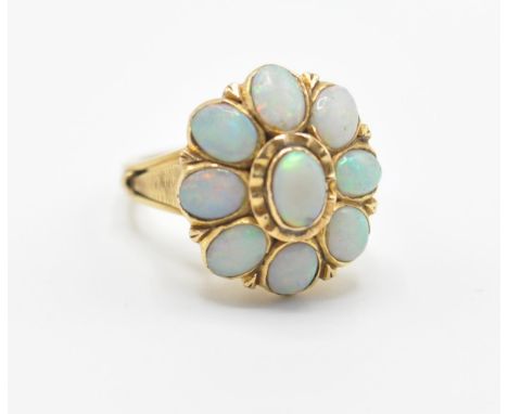 An 18ct gold lady’s dress ring having a flower head set with nine oval opal cabochons with pierced shoulders. Unmarked but te