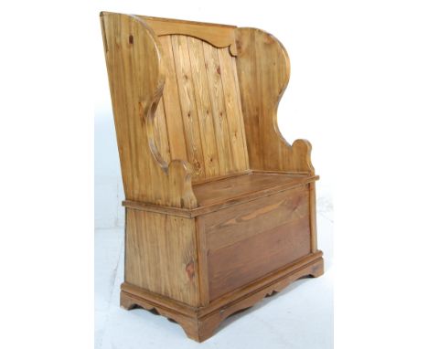 A contemporary antique style vintage two seat country pine pine monks bench with shaped arm rests and winged headrest having 