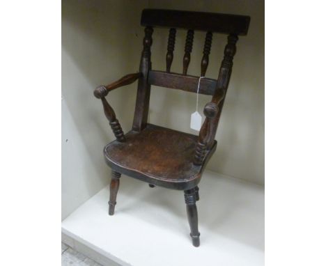 A late 19thC stained beech doll's elbow chair with a bobbin turned back and solid seat       OS3