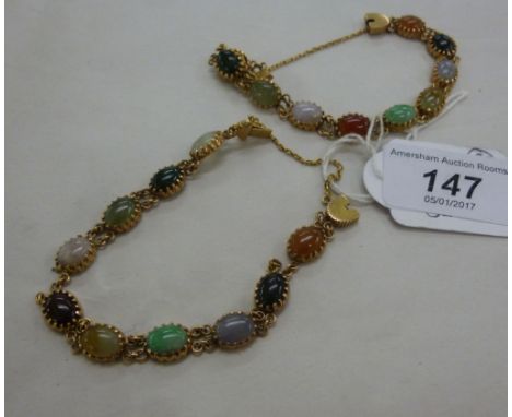 A pair of yellow metal bracelets on safety chains, claw set with various cabochon jade, jasper and other coloured hardstones 