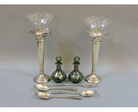 A pair of silver vases, with glass insets, a pair of green glass scent bottles with silver overlay, a silver pickle fork, and