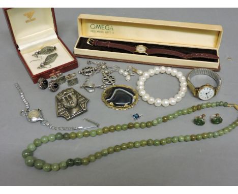 A ladies cased 9ct gold Omega mechanical strap watch, a pair of cased nephrite earrings with screw fittings marked 9ct, a row