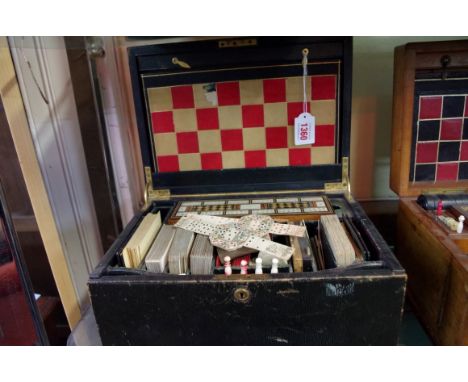 A Victorian green leather games box, with hinged lid and fall front enclosing a boxwood and ebonized chess set and playing co