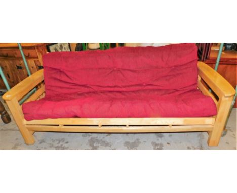 A pine framed sofa bed, with red upholstered seat and drop down back, 90cm high, 219cm wide, 92cm deep.  Upon initial inspect