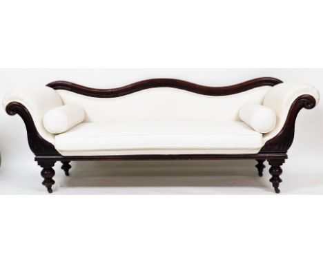 A late Victorian mahogany framed sofa, with serpentine shaped moulded back, with carved scrolling arms on turned legs and cas