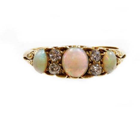 An 18ct gold opal and diamond dress ring, set with three oval opals and four tiny diamonds, in scroll carved raised ring head