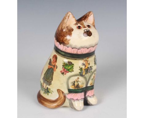 A Joan and David De Bethel Rye pottery cat, dated 1992, typically modelled seated, its cream clothing with découpage children