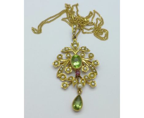An Edwardian yellow metal set, peridot, ruby and seed pearl pendant on a 9ct gold chain, 4.6g, height of pendant 43mm