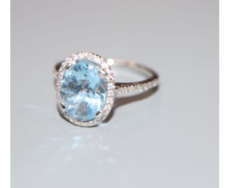 A modern aquamarine and diamond set oval dress ring, with diamond set shoulders, 18ct white gold setting, size J/K, gross 3.5