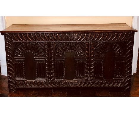 An Elizabethan oak plank chest, circa 1560, hinged rectangular top above three panel front carved in high relief with archite