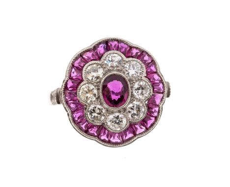 A ruby and diamond platinum flower cluster, the principal oval cut ruby measuring approx. 4.7mm x 3.8mm, 2.3mm, surrounded by