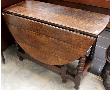 An early 18th Century joined oak gateleg table, having a two plank top, the leaves each formed of three planks, the central b