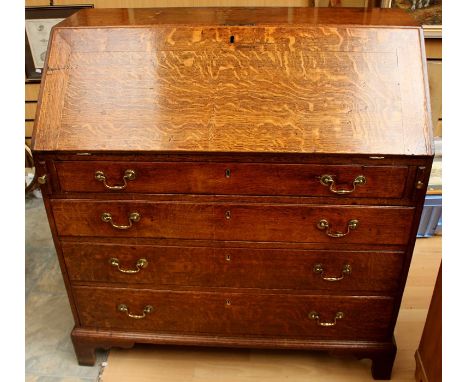 A George III oak bureau, circa 1770, the fall front opening to reveal a fitted interior comprising drawers, a central door an