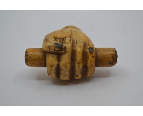 A carved Ivory walking stick handle in the form of a clenched fist holding a rod.