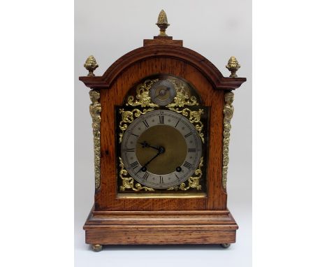 An early 20th Century oak bracket clock, with brass and silvered face, eight day movement, Roman numerals, 38 cms high, 24 cm