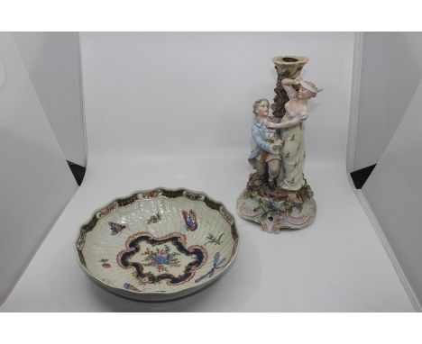 A German porcelain figural candlestick, in the form of a young gentleman proposing to a young lady, the man in a blue overcoa