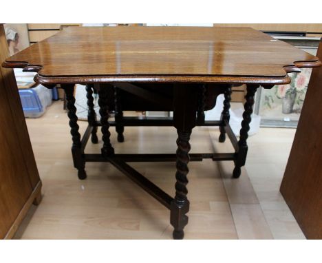 An early 20th Century oak gateleg table, circa 1930, the leaves with a shaped edge, raised on barley twist legs, joined by sq