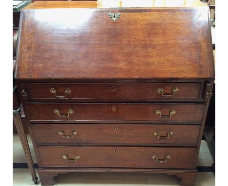A George III oak and mahogany cross banded bureau, the fall front enclosing a fitted interior, four drawers below, bracket fe