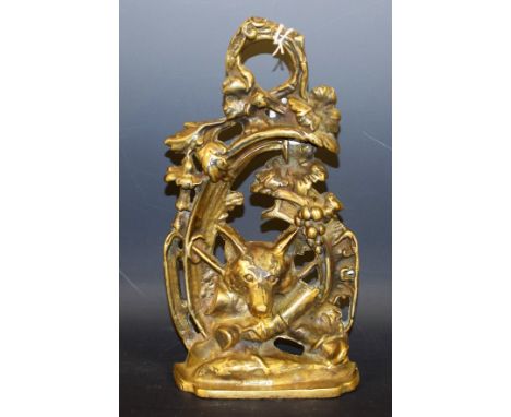 A early 20th century brass door stop, cast with a fox mask and hunting regaila within an arbour of fruiting vine, 27cm high