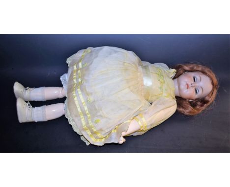 A bisque head doll, in the style of Kammer & Reinhardt, with sleeping eyes,  closed mouth, auburn wig,  incised K star R, Sim