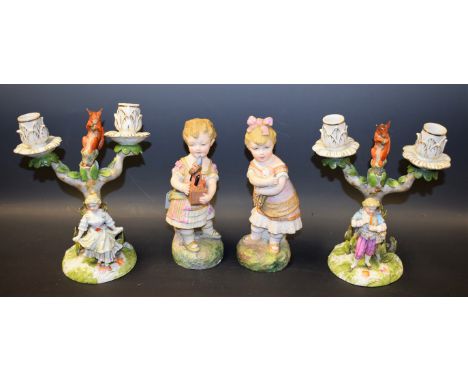 A pair of late 19th century German porcelain figures, Children at Play; a pair of similar two branch candelabra, with squirre
