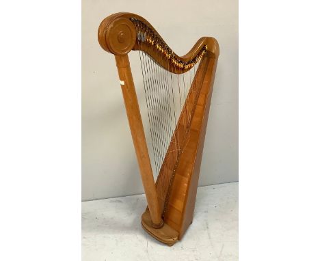 A freestanding light oak harp, with turned decoration to top, some strings missing, raised on four turned bun feet, 137cm tal