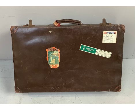 A vintage brown suitcase with travel stickers, 71cm wide 