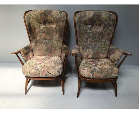 A pair of stick back Ercol armchairs with floral upholstered cushions, 103cm high 