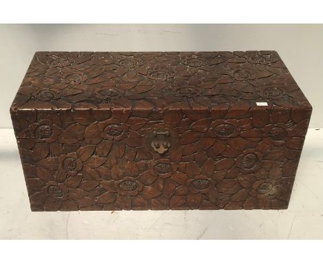 An Oriental camphor lined heavily carved wooden blanket box / trunk, carved with scrolling flowers, raised on bracket feet (o