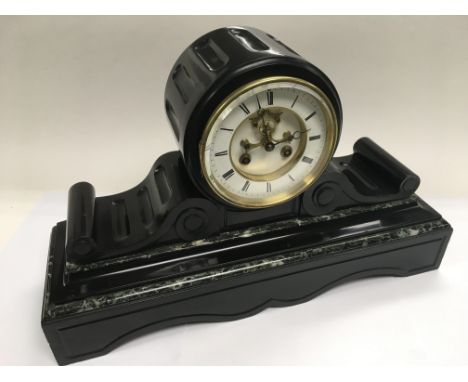 An 8 day slate and marble mantle clock with scrollwork decoration, the white clock face having Roman numerals.