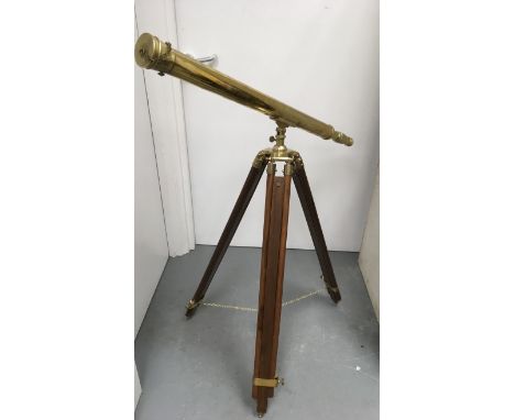 A large floorstanding brass telescope on extending wooden tripod base.Height approx 81cm x 1.2 metre long