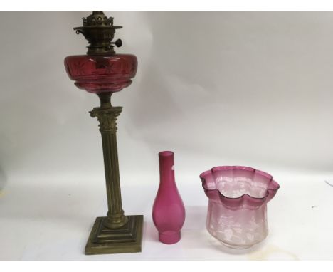 A Victorian Corinthian column oil lamp with engraved Cranberry shade, a Cranberry shade and cranberry reservoir.