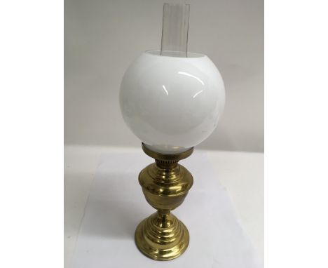 A brass oil lamp with glass globe shape shade